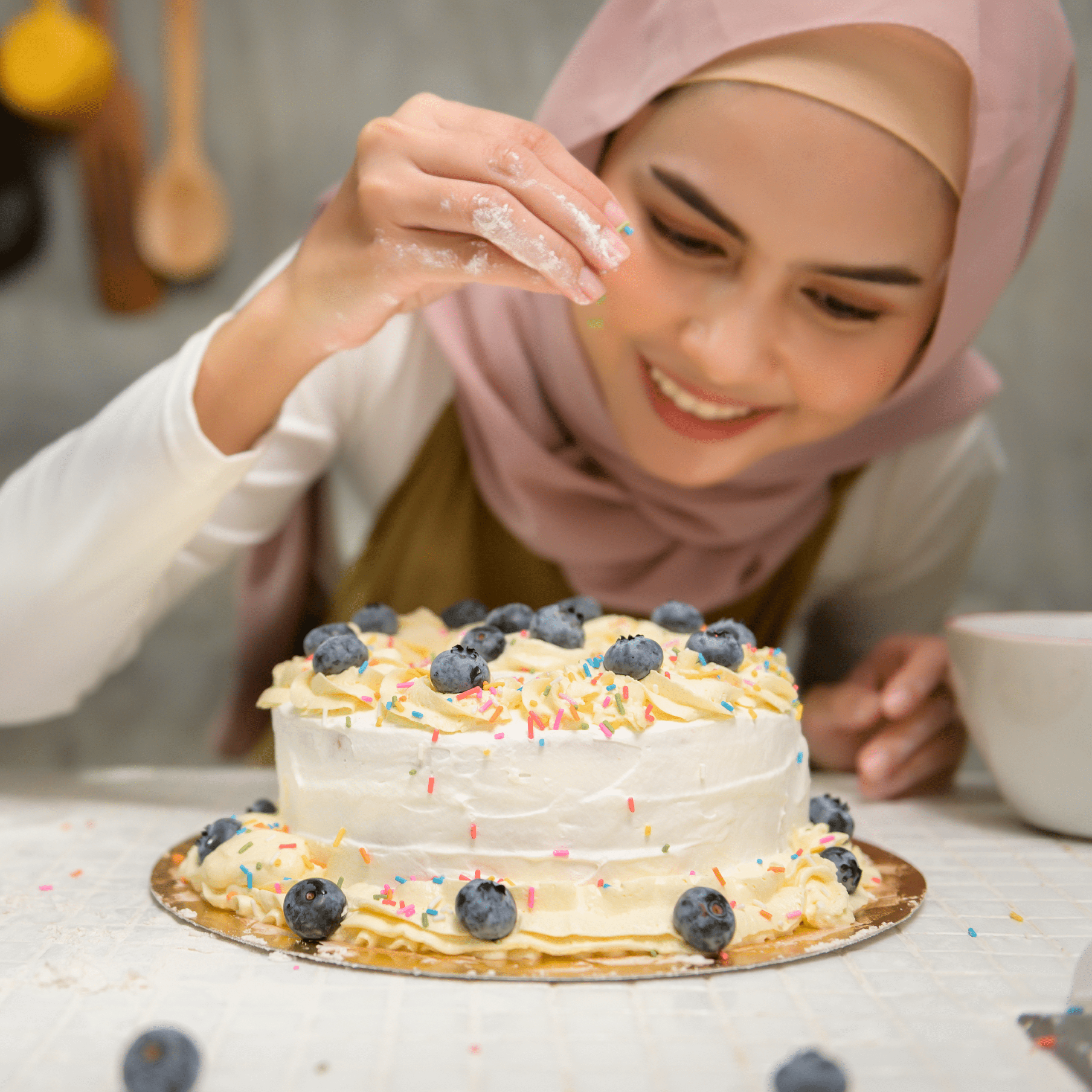 Sara decorating a homemade cake with blueberries and sprinkles in her kitchen