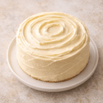 Finished Buttercream Cake with smooth, creamy frosting and soft spiral swirls on top, displayed on a simple plate with a clean, classic look.